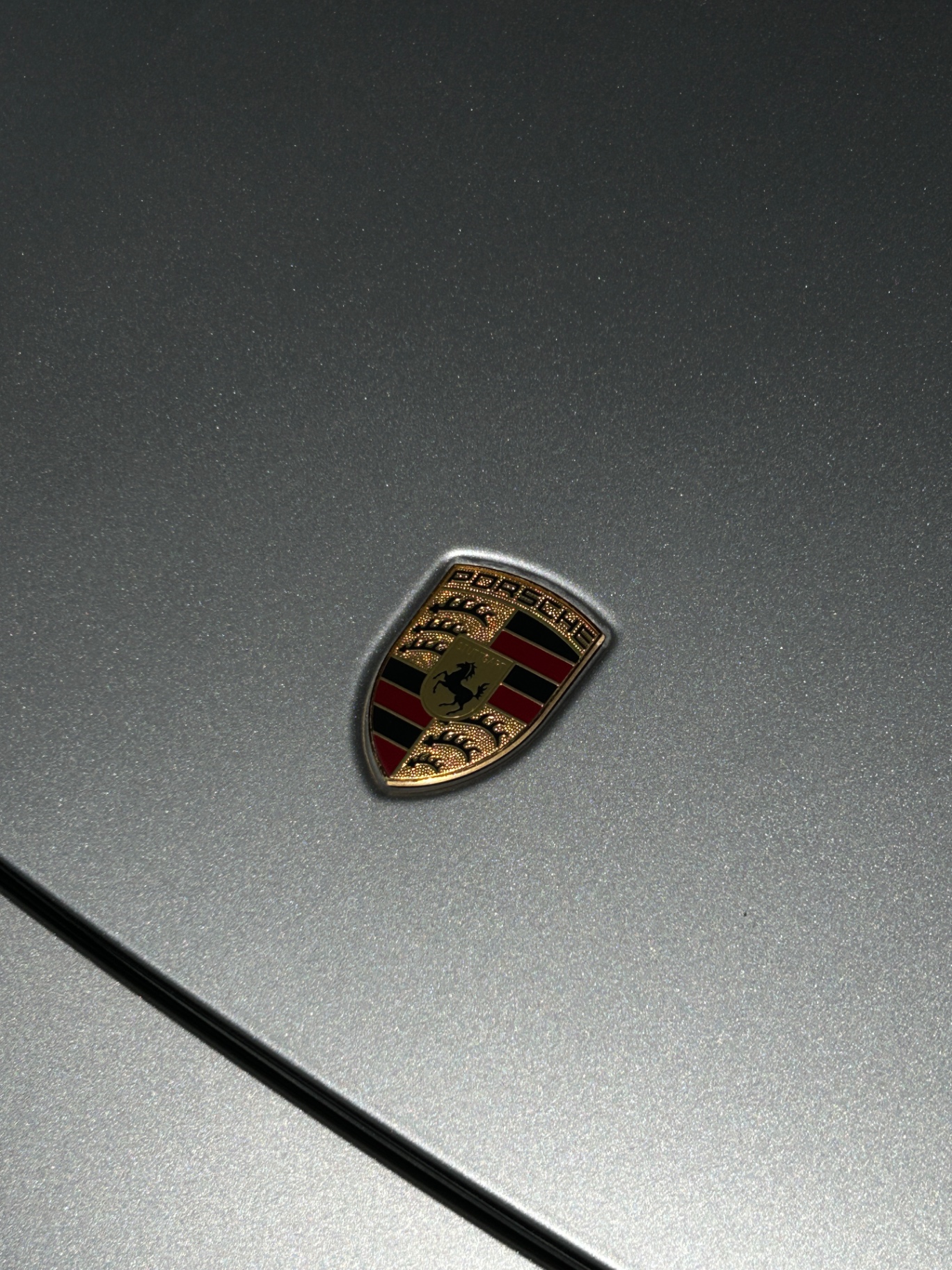Macro detail of a polished Porsche crest after ceramic coating